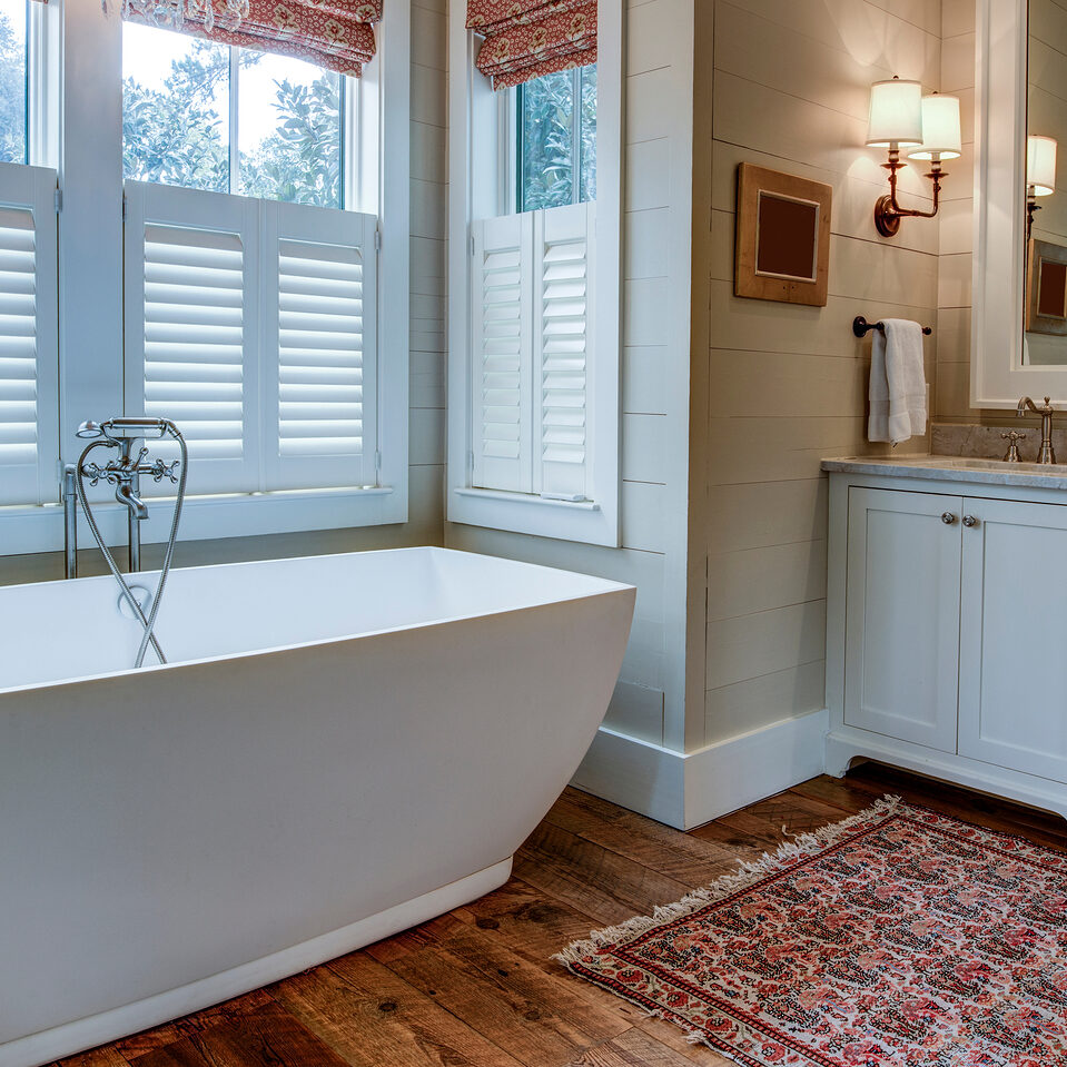 Luxury bathroom with large white tub, beautiful cabinets, and shiplap walls.