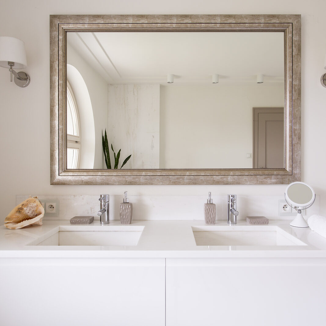 Cropped shot of a white vanity top with two sinks and a stylish mirror in bathroom interior